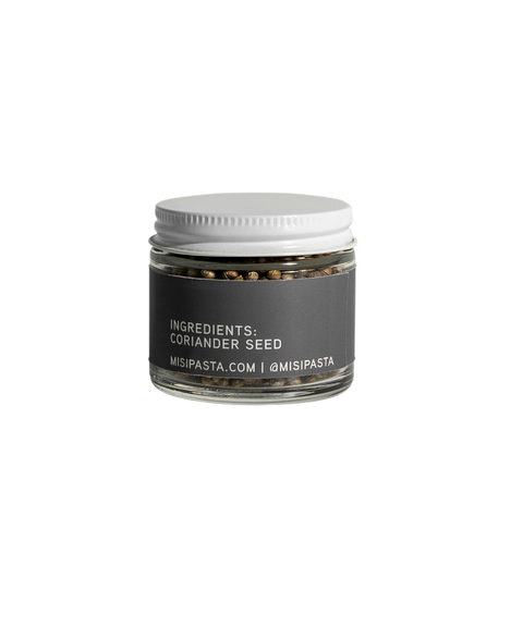 Jar of coriander seed with a white lid on a white background